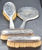 A George V silver mounted four-piece brush set, comprising hand mirror, hair brush and two clothes