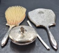 A white metal and white metal mounted four-piece dressing table set, comprising a hand mirror,