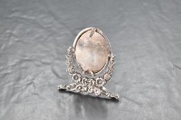A late Victorian silver photograph frame, of oval form pivoted between foliate moulded uprights