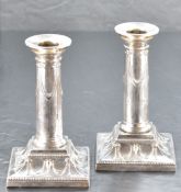 A pair of Edwardian silver candlesticks, having removable bead moulded sconces over ribbon and