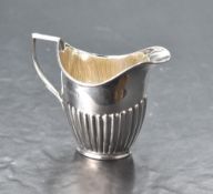 An Edwardian silver helmet-form cream jug, with angular handle and half gadrooned body, marks for