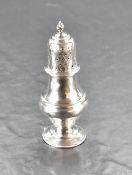A George V silver pepperette, of dredger form with pierced finial topped cover over the moulded body