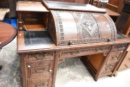 An impressive 19th Century dark oak roll top desk having carved rose and rams head decoration,