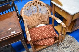 A vintaged armchair with canework back and solid seat