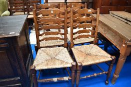 A set of four traditional shaped ladder back kitchen chairs having rush seats
