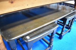 A dark stained Ercol style coffee table having two smaller tables nesting beneath, approx 114 x