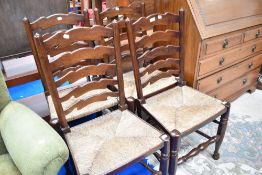 A set of four oak ladder back dining chairs having rush seats