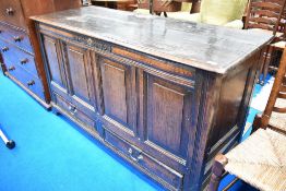A period oak kist having panelled doors to sides, monogram and date carved to front above the four