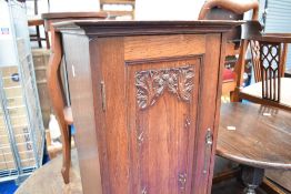 A Victorian mahogany pot cupboard, the panelled door having carved thistle decoration
