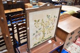 An early 20th Century oak fire screen with embroidered panel