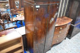 An early 20th century regency revival single bow fronted wardrobe