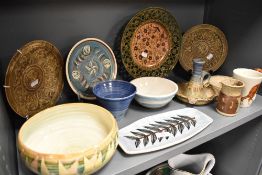 A shelf of studio pottery including bowls, dishes, plates and a brutalist style chamber stick.