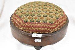 An antique button shaped foot stool with embroidered top.