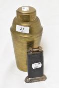 An Art Deco brass cocktail shaker with an early 20th century Dunhill table top lighter.