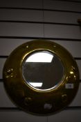 An early 20th century Art and Crafts style button form brass mirror. 33cm wide.