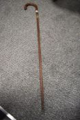An antique textured wood walking cane having silver cuff to shaft and silver pips to handle.