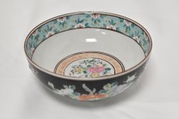 A Chinese porcelain bowl decorated in famille noir with scenes of exotic birds.
