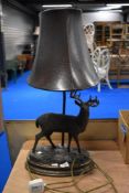 A modern table lamp having a resin cast deer figure and leather shade