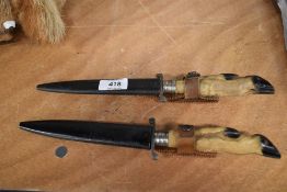 A pair of vintage hunting knives with metal scabbards and small deer hoof handles