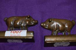 A pair of small cast bronze cast mirrored pig ornaments.