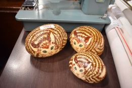 A set of three graduated painted stones in the form of a curled up cat.