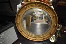 An early 20th century convex butlers mirror with gilt ball circular frame.