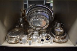 A large shelf full of silver plated serving dishes, trays, plates and condiments.