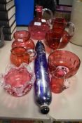 A collection of vintage cranberry glass wares including water jugs, vases and bowls.