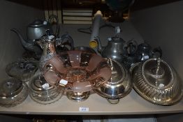 A shelf of early 20th century silver plated serving wares including lidded dishes, glass tazza,