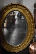 A large Victorian oval bevel edged mirror with a gilt and gesso frame. 95cm x 70cm