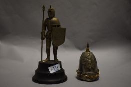 Two military related table top cigarette lighters one in the form of a helmet and a similar