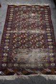 An antique North West Persian rug in a red ground with heavy wear.