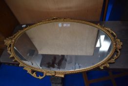 A gilt metal wall mirror having scroll decoration