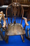 An early 20th century elm wood seated wheel back rocking chair.