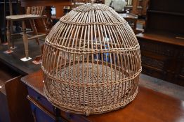 An antique bird cage in woven wicker, having some worm.