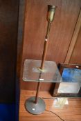 An early 20th century library lamp with brass and turned wood base and glass shelf.