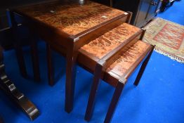 A mid century nest of three teak tables with a sunflower tile top.