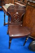 A Victorian hall way chair having solid mahogany frame with carved shield back.