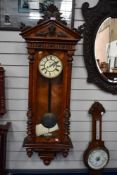 A Victorian Vienna style wall clock having mahogany case with enamel face and carved details.