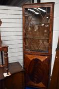 An early 20th century corner cabinet with under cupboard and glazed astral doors, with flame