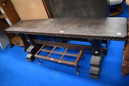 A dark stained oak Refectory style bench with carved details.