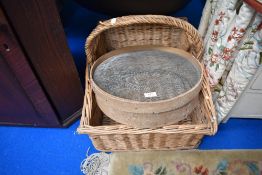 A vintage wicker log basket with handle and a sieve.
