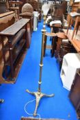 An early 20th century standard lamp in brass on tripod base with adjustable shaft.
