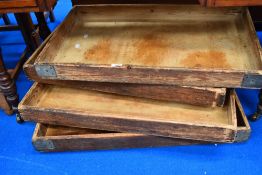 A stack of four vintage bakers bread trays.