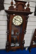 A Victorian Vienna style wall mounted clock with an enamel face and carved mahogany frame.
