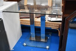 A modern glass topped dining table with chrome base