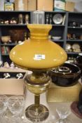 A vintage brass effect and glass paraffin lamp with broad orange/brown glass shade