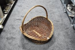 A large woven-wicker harvest/flower display basket with over-handle 59cm wide