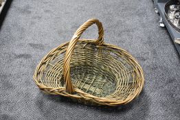 A large woven-wicker harvest or flower display basket, of pinched oval form with over-handle, some