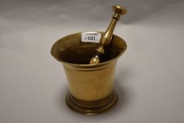 A 19th century brass mortar in typical fluted bell form with a double baluster and central knop